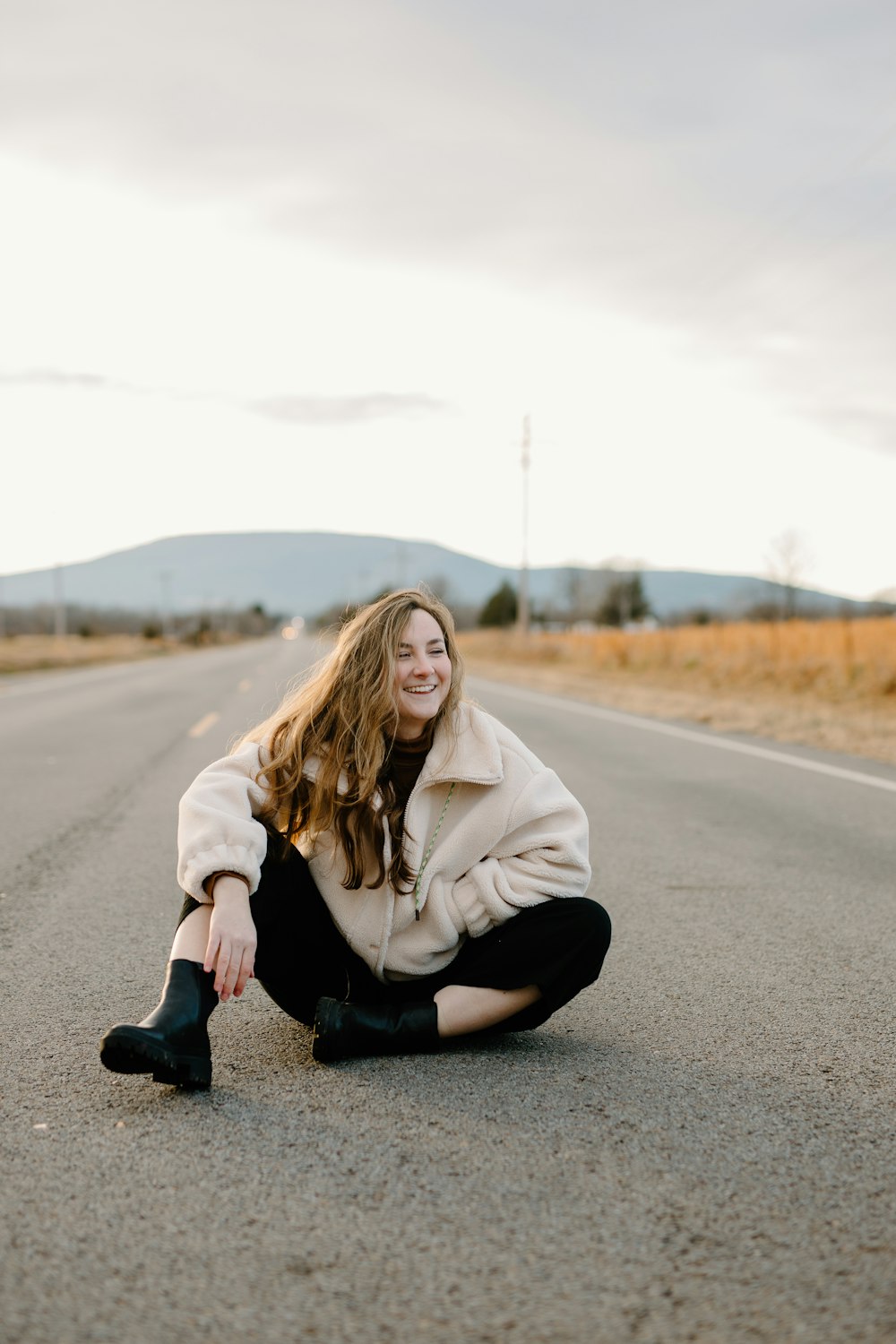 woman in gray hoodie sitting on road during daytime