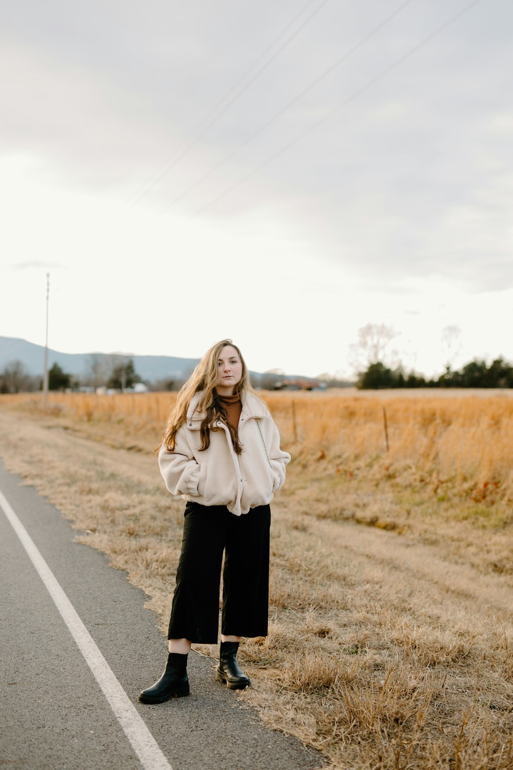 woman in white jacket standing on road during daytime