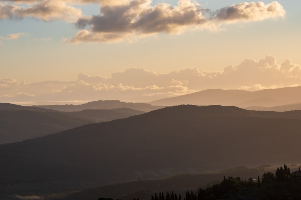 green trees and mountains under white clouds