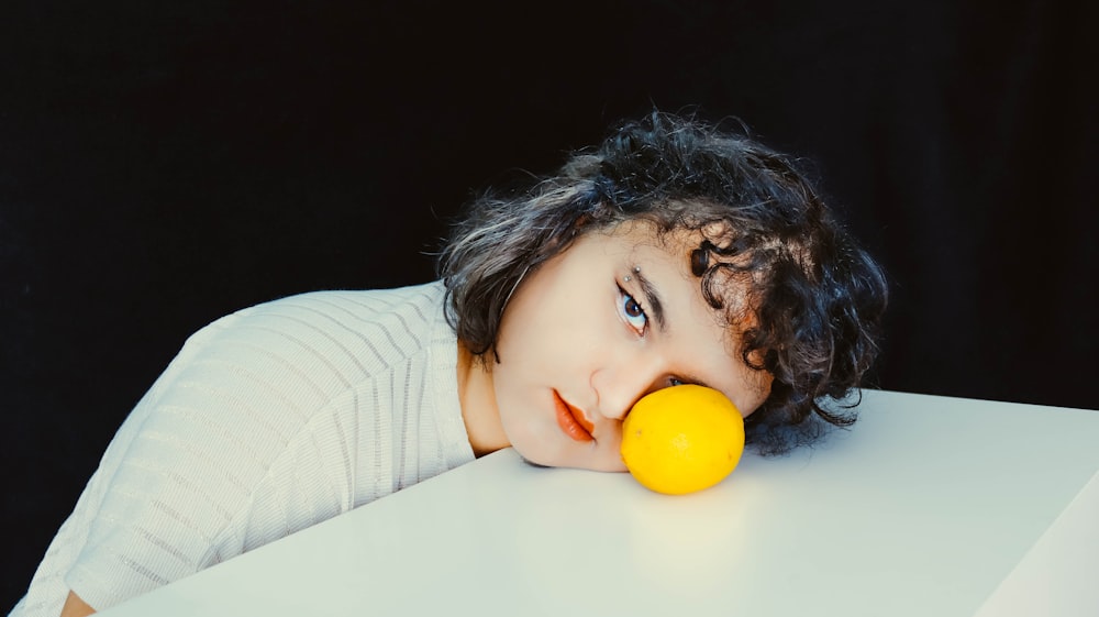 girl in white and gray striped long sleeve shirt holding orange fruit