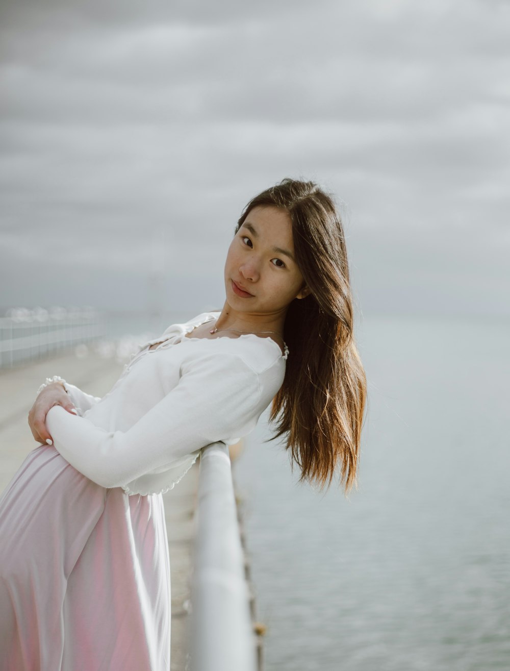 woman in white long sleeve shirt standing near white metal fence during daytime