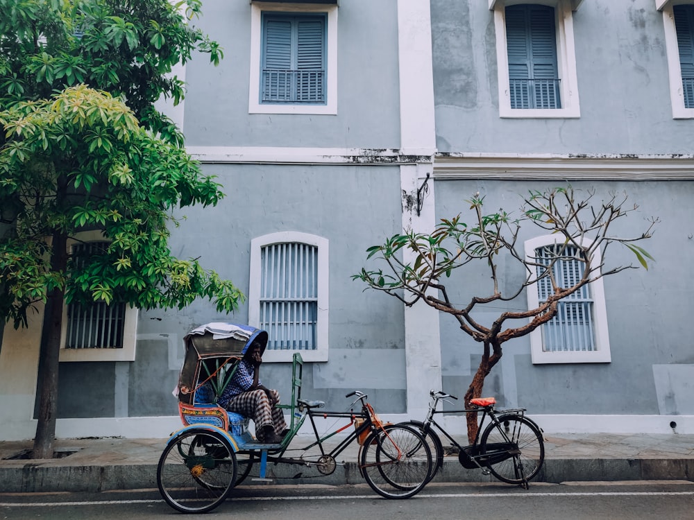 bicicleta urbana vermelha e preta estacionada ao lado de um edifício de concreto branco durante o dia