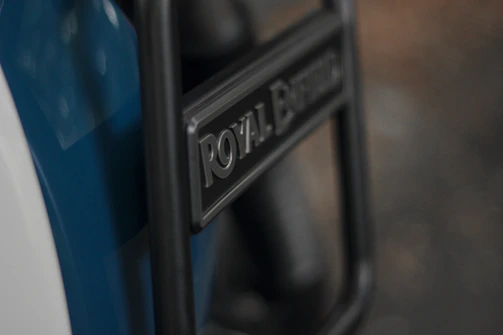 Close-up of a Royal Enfield badge gleaming under the sunlight on a freshly purchased bike.