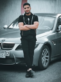Professional male sales advisor dressed smartly standing confidently beside a modern car.