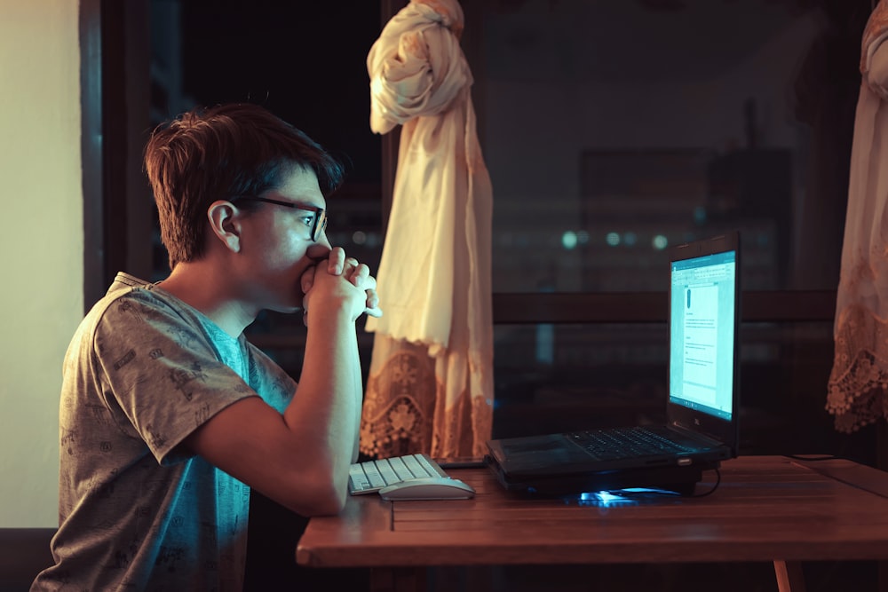 Mujer en camisa marrón sentada frente a la computadora portátil