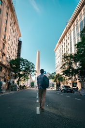 man in black jacket and brown pants standing on sidewalk during daytime