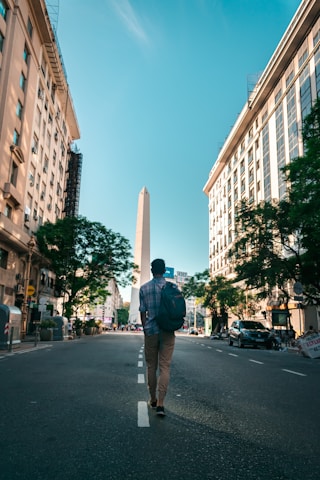 man in black jacket and brown pants standing on sidewalk during daytime