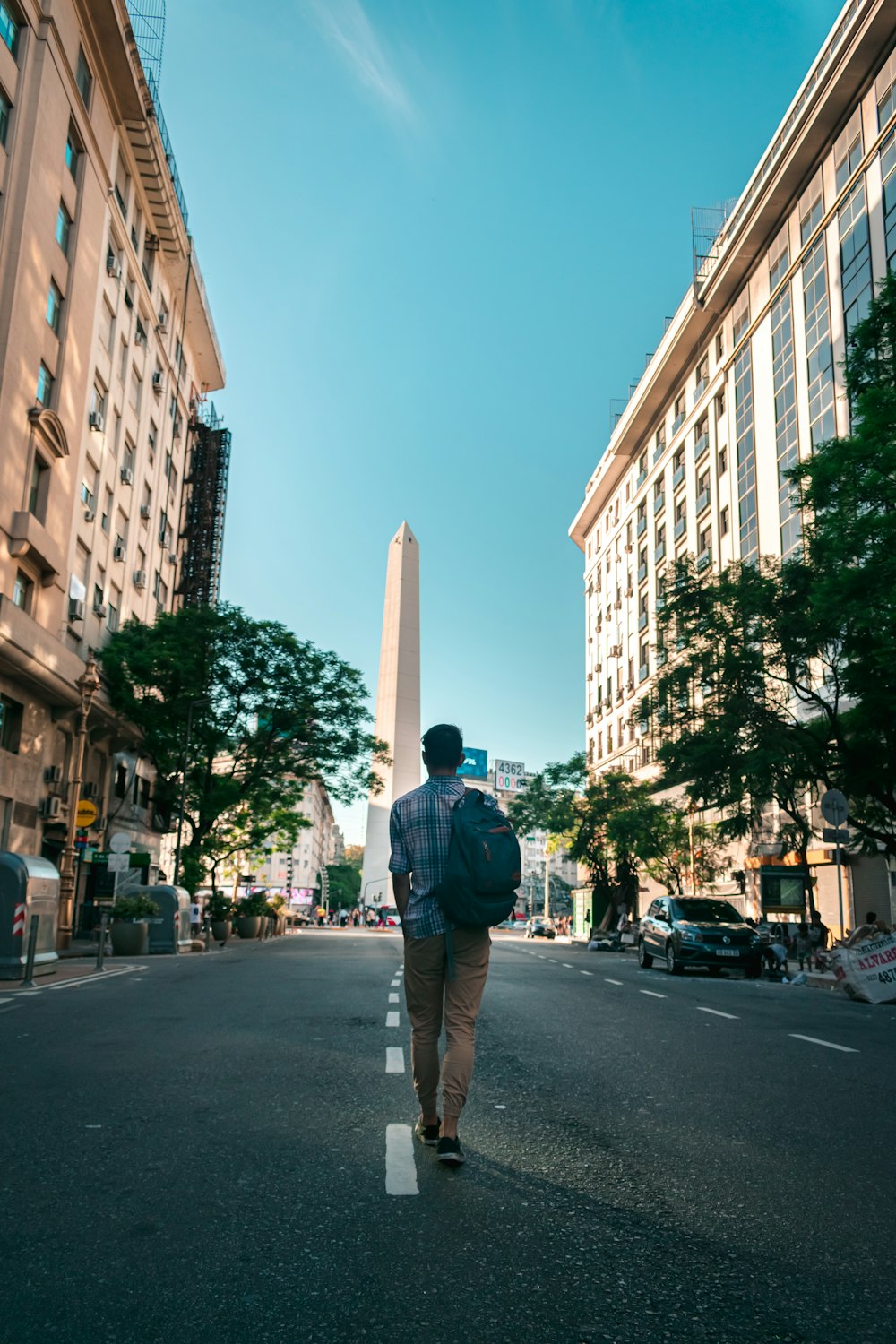 man in black jacket and brown pants standing on sidewalk during daytime