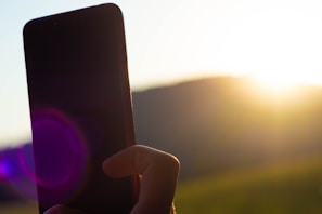 Smartphone in hand with a bright outdoor background emphasizing portability