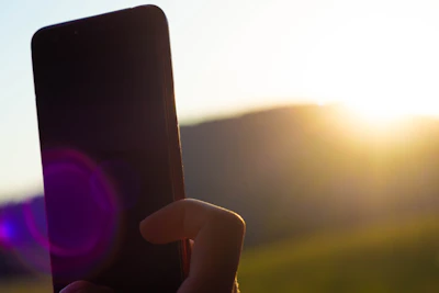 User interacting with a Luxora app outdoors, sunlight highlighting the screen.