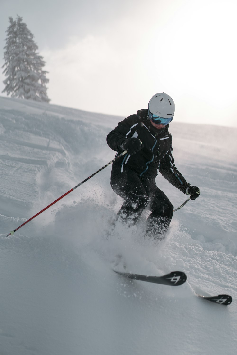 person in black jacket and black pants riding on ski blades on snow covered ground during