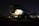 A partially disassembled airplane with the nose cone removed is situated in a dark, possibly abandoned setting. It is propped up on blocks, and some parts are missing, exposing fixtures and structures. The atmosphere is dimly lit, with faint illuminate on the body's side revealing the number 357.