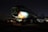 A partially disassembled airplane with the nose cone removed is situated in a dark, possibly abandoned setting. It is propped up on blocks, and some parts are missing, exposing fixtures and structures. The atmosphere is dimly lit, with faint illuminate on the body's side revealing the number 357.