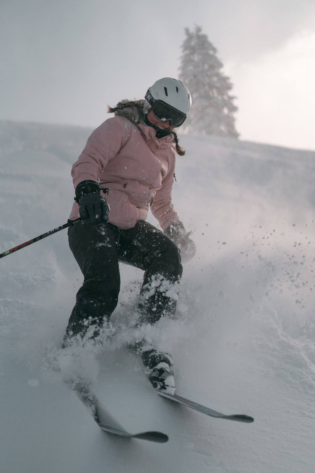 man in pink jacket and black pants playing ski on snow covered ground during daytime