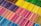 An array of colored pencils arranged in neat, parallel rows, sorted by color. The pencils form a vibrant pattern with a spectrum of shades ranging from cool blues and purples to warm reds, yellows, and greens.