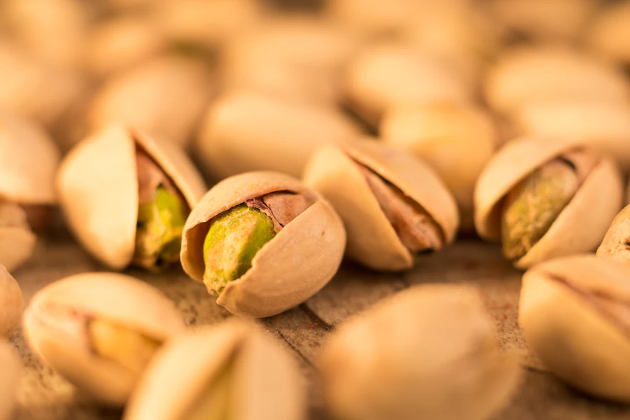 Roasted pistachios in their split shells on a wooden bench
