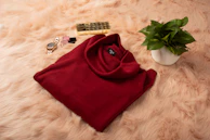 A cozy cream sweater with subtle sparkly accents folded neatly beside a Barbie pink scarf.