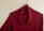 Close-up of a colorful sweater draped on a wooden hanger against a clean white wall