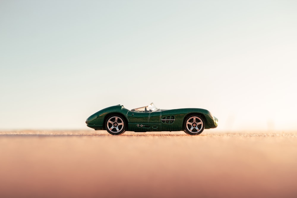 green coupe on brown sand during daytime