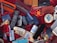A variety of disparate objects are arranged on a red fabric surface, including multiple old mobile phones, a television remote control, a fidget spinner, a razor in an orange case, and several leather wallets. Other items include a shoe brush, writing pens, a small MP3 player, and a bar of soap. The collection features miscellaneous everyday items and novelties.