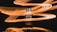 A bottle of perfume is placed against a dark background. Surrounding it are dynamic, swirling light trails in shades of orange and yellow that create a sense of motion and energy.