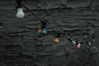 A cluster of colorful bulb lamps hanging at different heights against a neutral wall