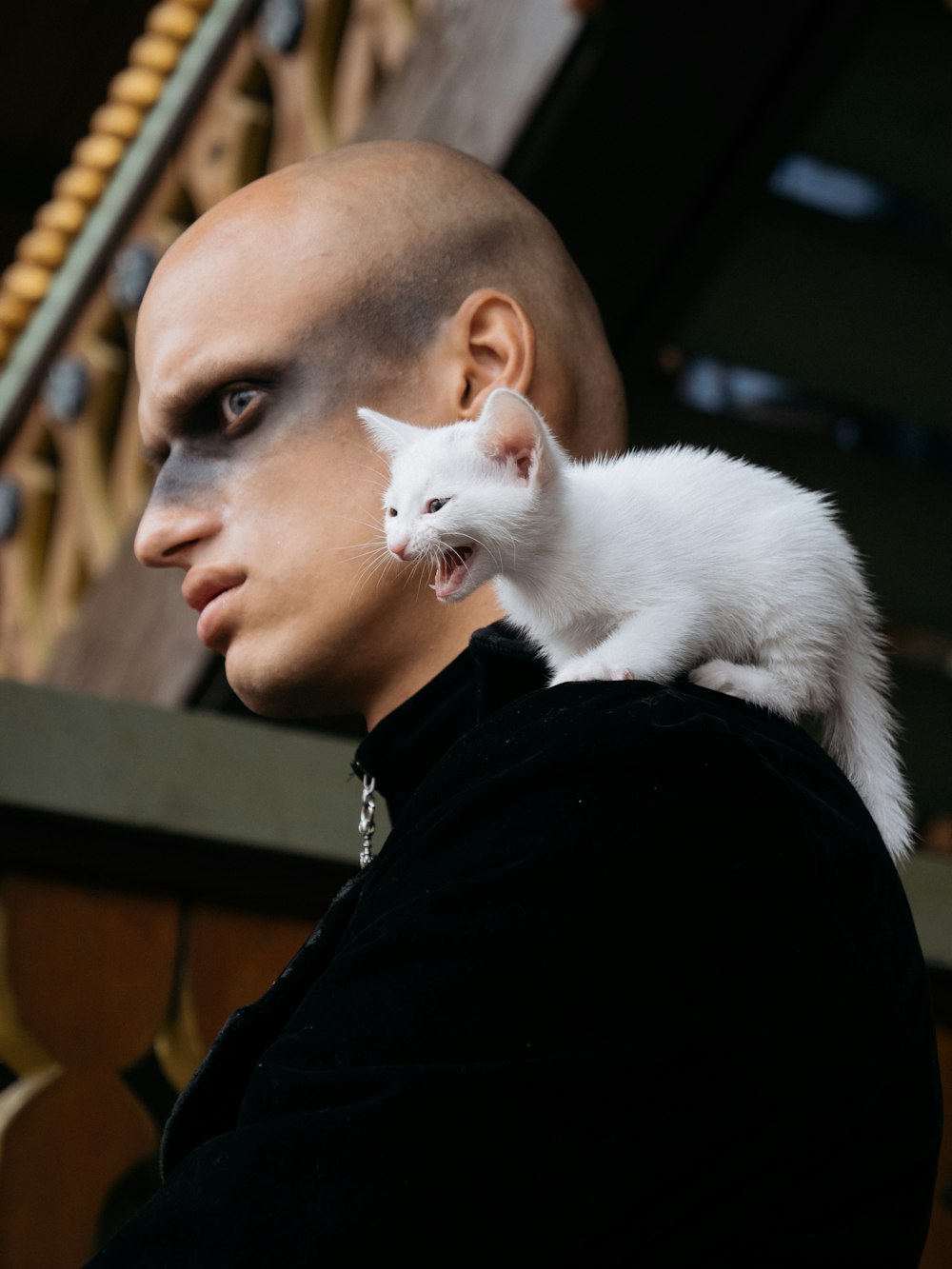 man in black shirt with white cat on his shoulder