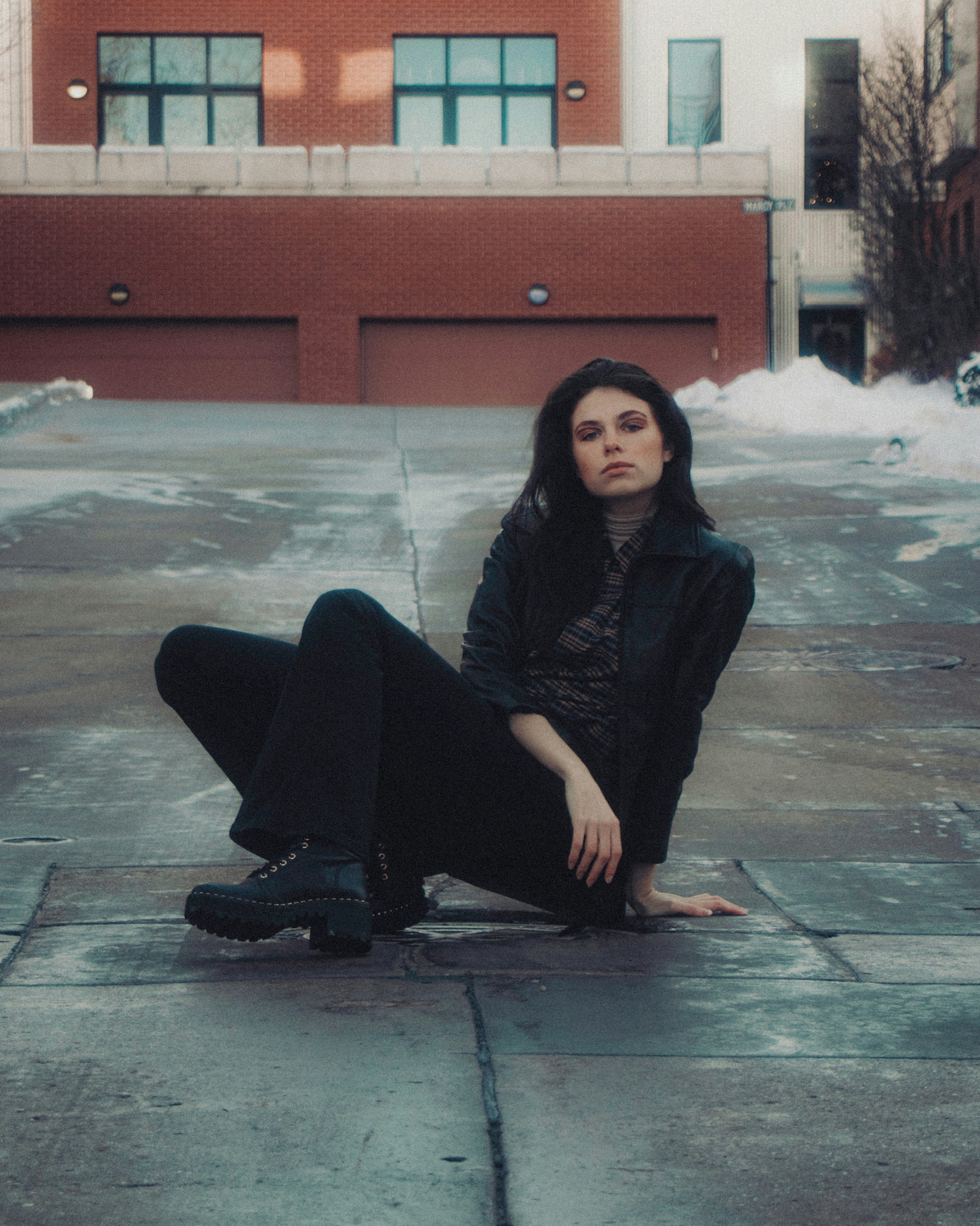 woman in black long sleeve shirt and black pants sitting on gray concrete floor