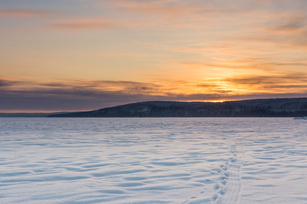 snow covered field during sunset