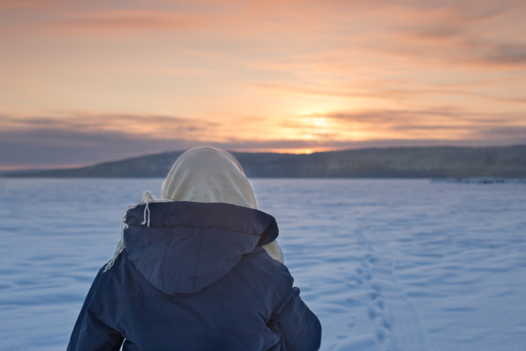 person in black jacket and white cap standing on snow covered ground during daytime