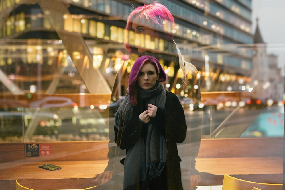 woman in black coat standing near glass wall