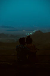 A couple enjoying a romantic dinner overlooking a scenic mountain landscape.