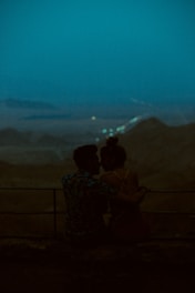 Couple enjoying a candlelit dinner overlooking a serene mountain lake at dusk.