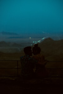 Couple enjoying a candlelit dinner overlooking a serene mountain lake at dusk.
