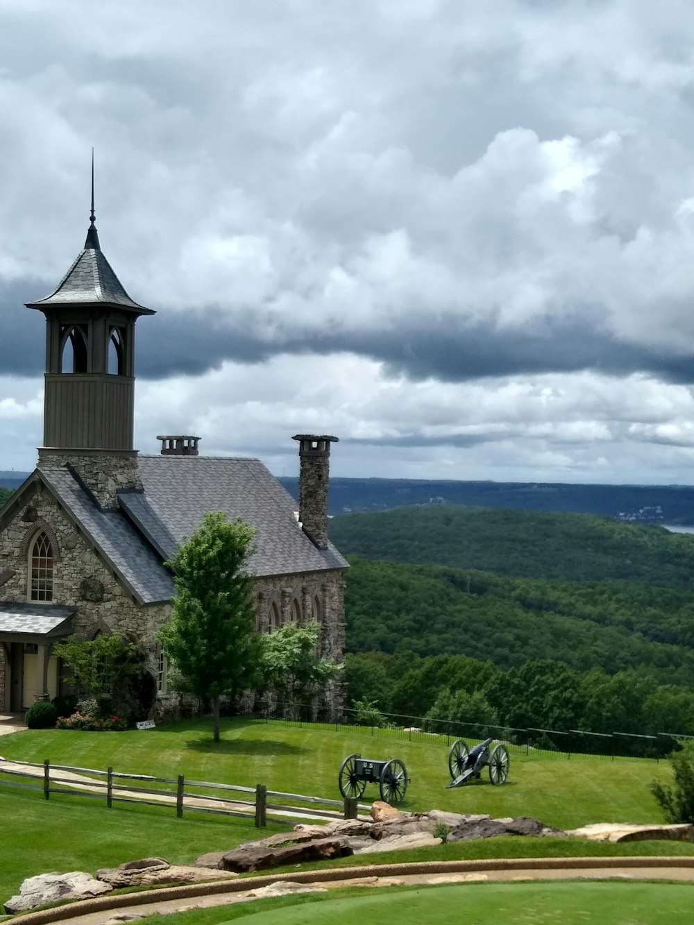 Bâtiment en béton brun près d’un champ d’herbe verte sous les nuages blancs pendant la journée