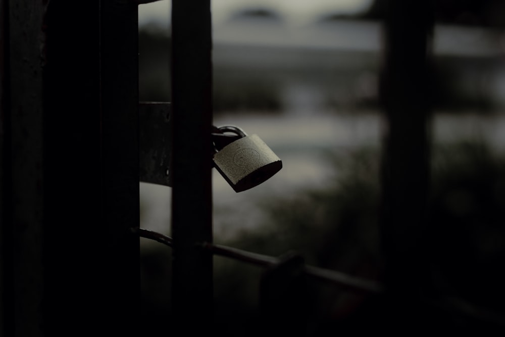 silver padlock on black metal fence