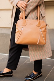 person in black pants holding brown leather handbag