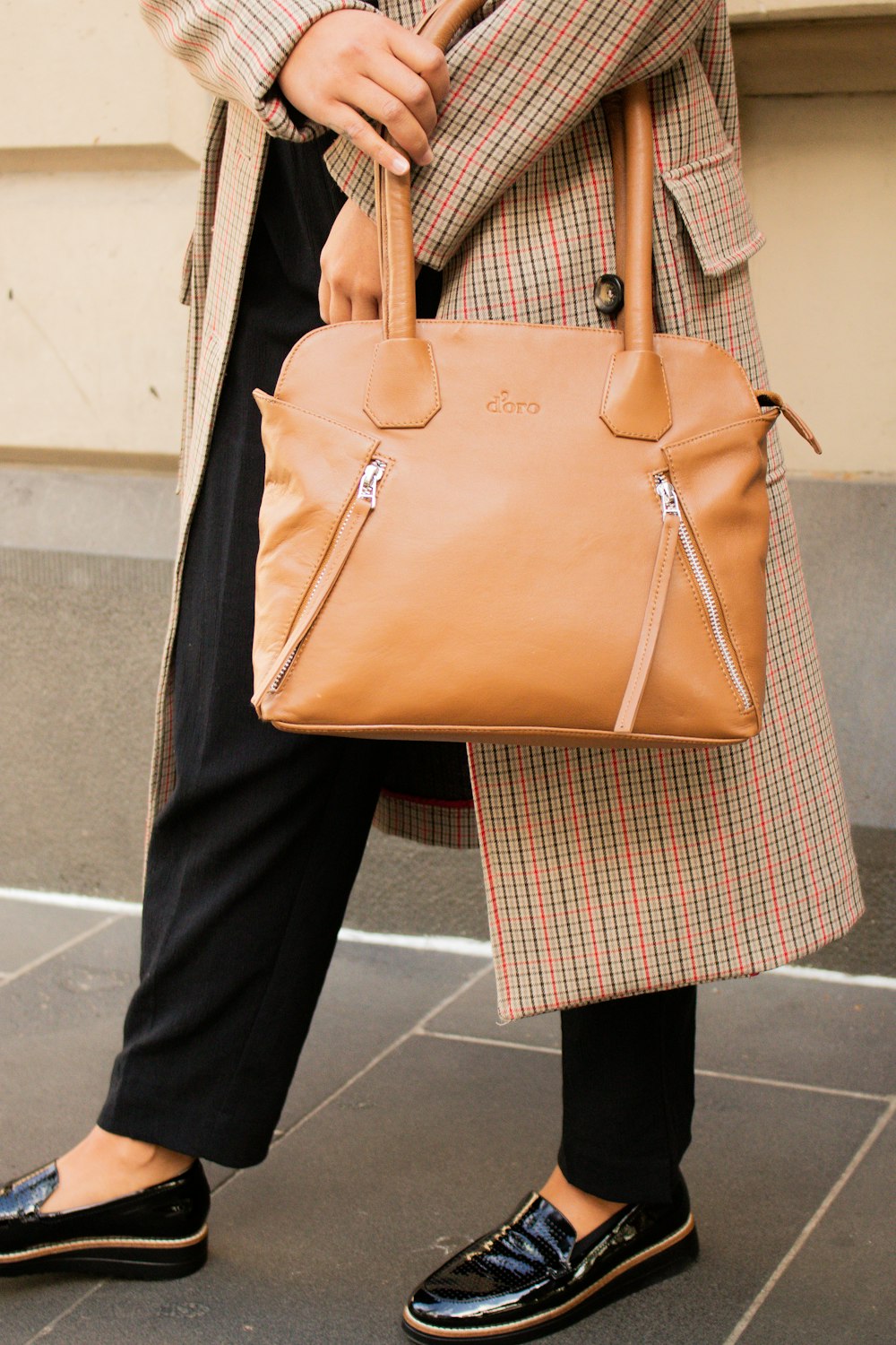 person in black pants holding brown leather handbag