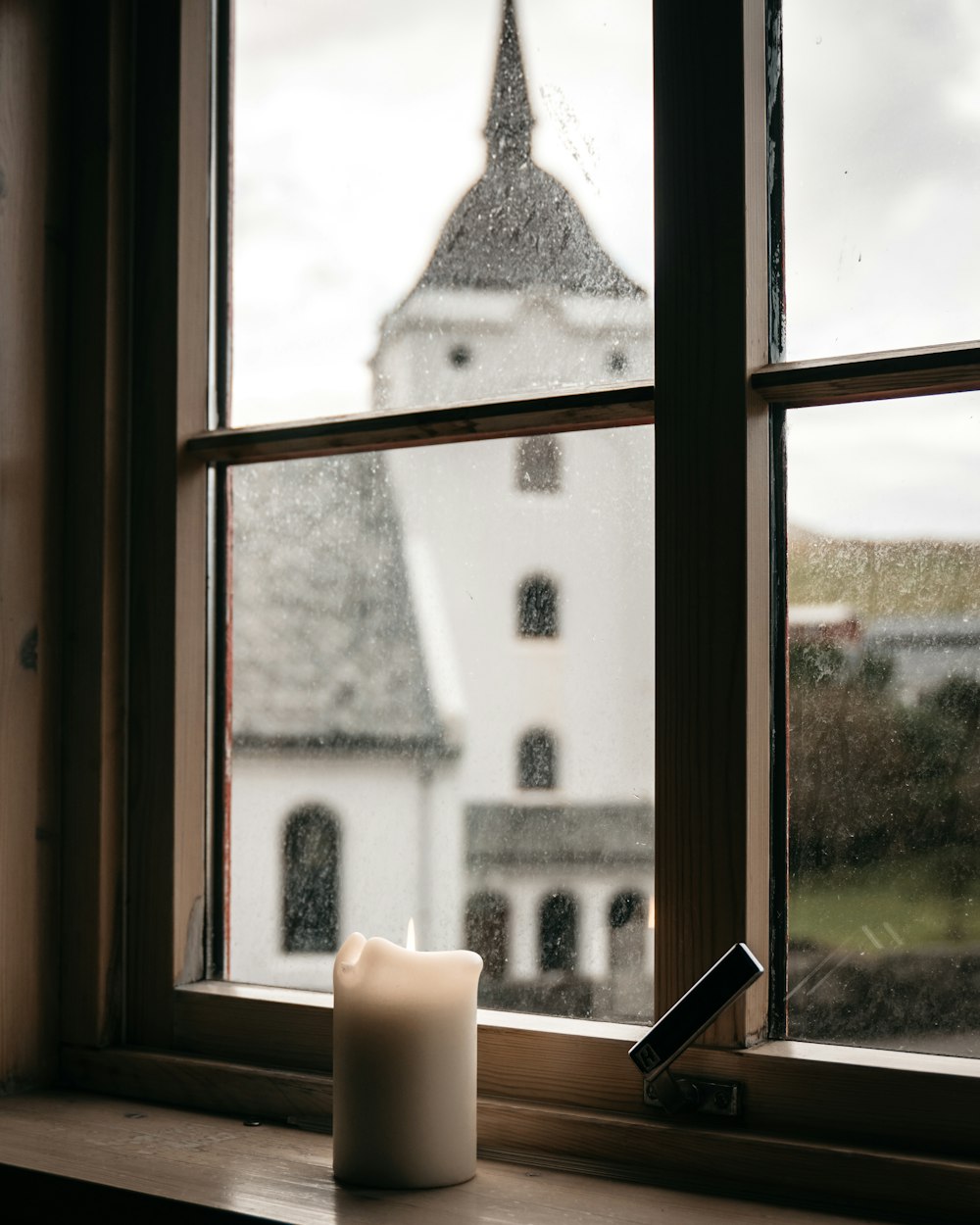 weiße Stumpenkerze am Fenster