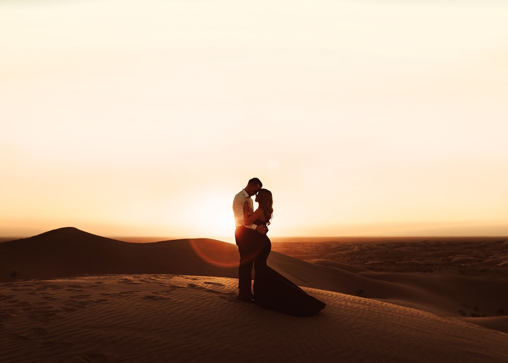 mulher no biquíni preto em pé na areia marrom durante o pôr do sol