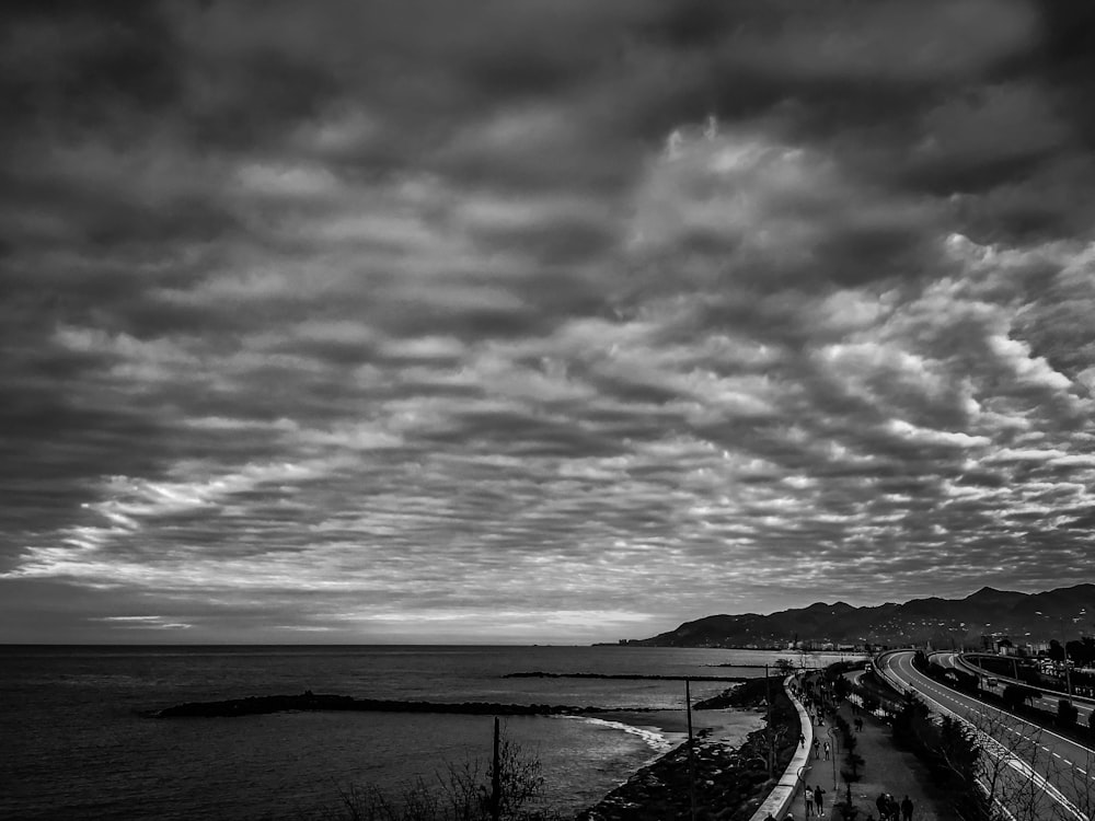 grayscale photo of road near body of water