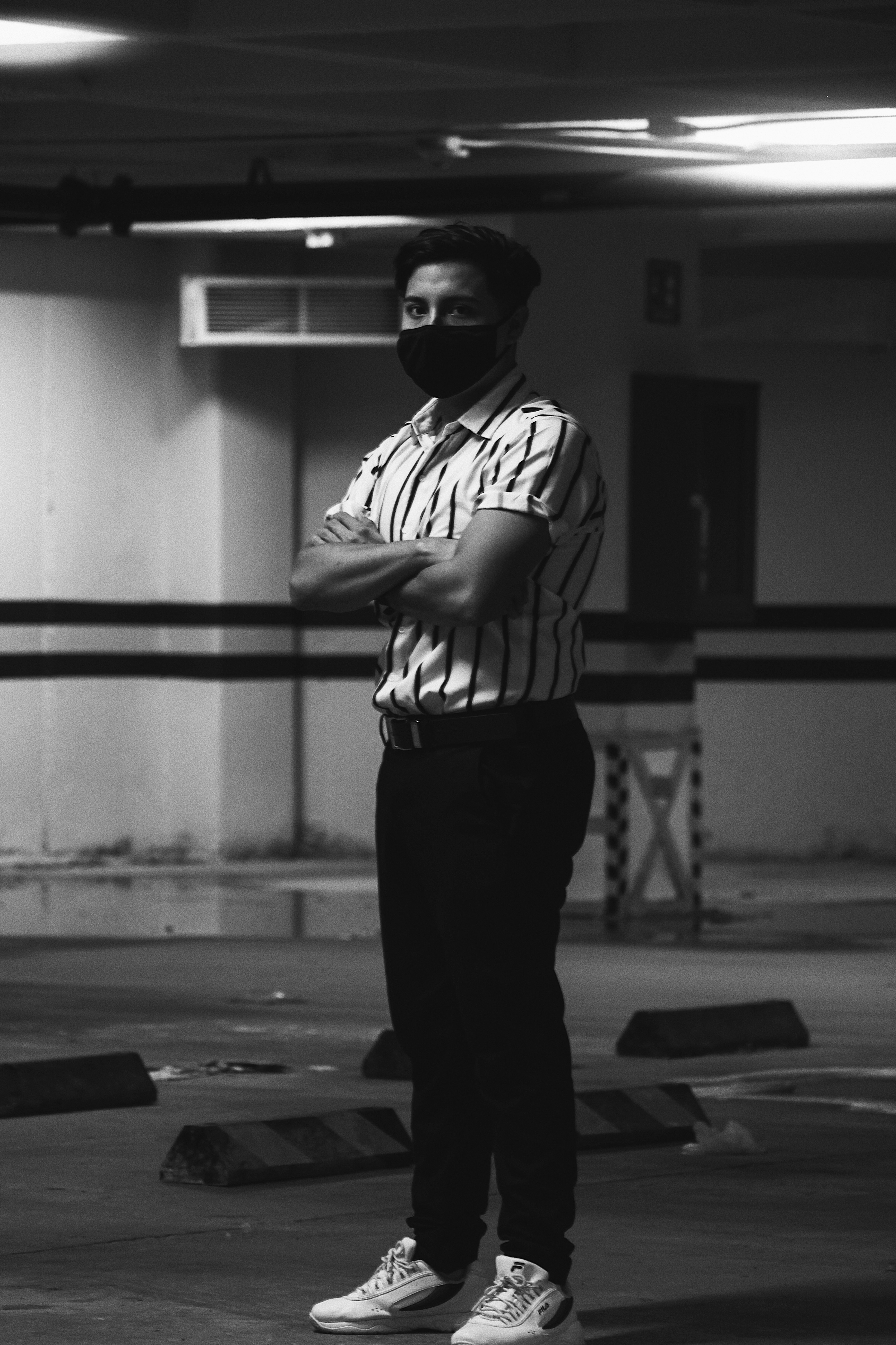 man in white and black stripe shirt and black pants standing in front of white wall