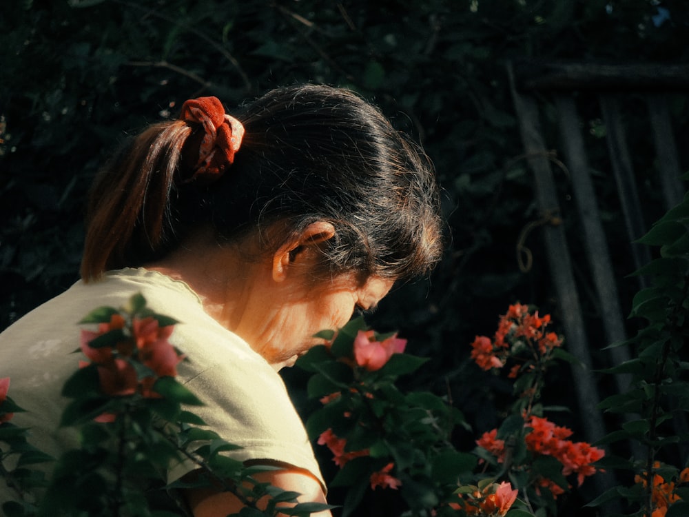 Frau im weißen Hemd steht tagsüber in der Nähe grüner Pflanzen