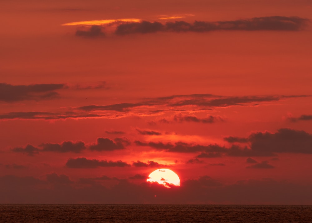 corpo de água sob o céu laranja durante o pôr do sol