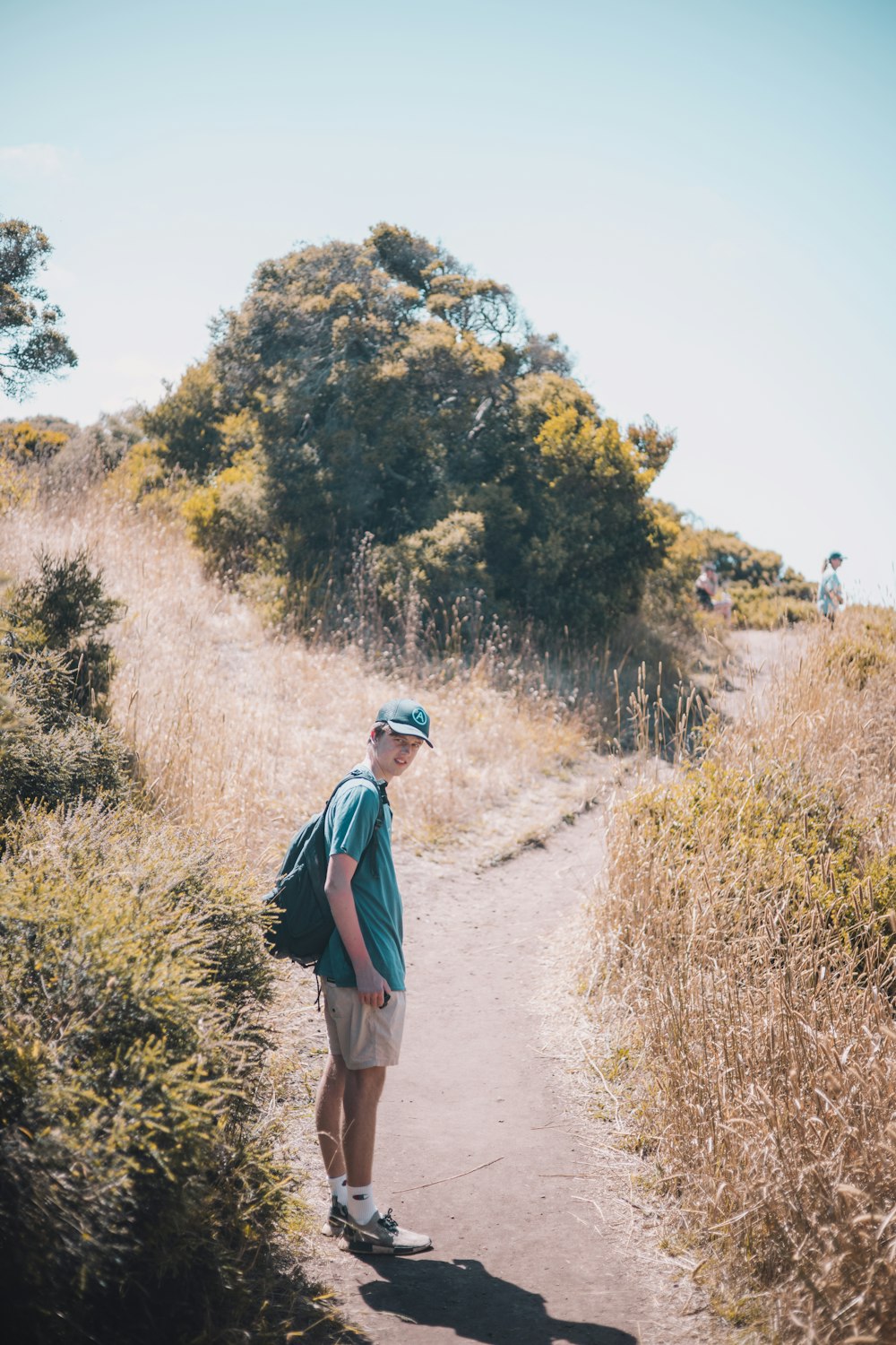 man in blue jacket walking on dirt road during daytime