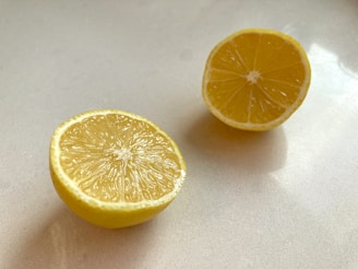 A fresh lemon sliced in half with droplets of juice sparkling in sunlight on a wooden table.