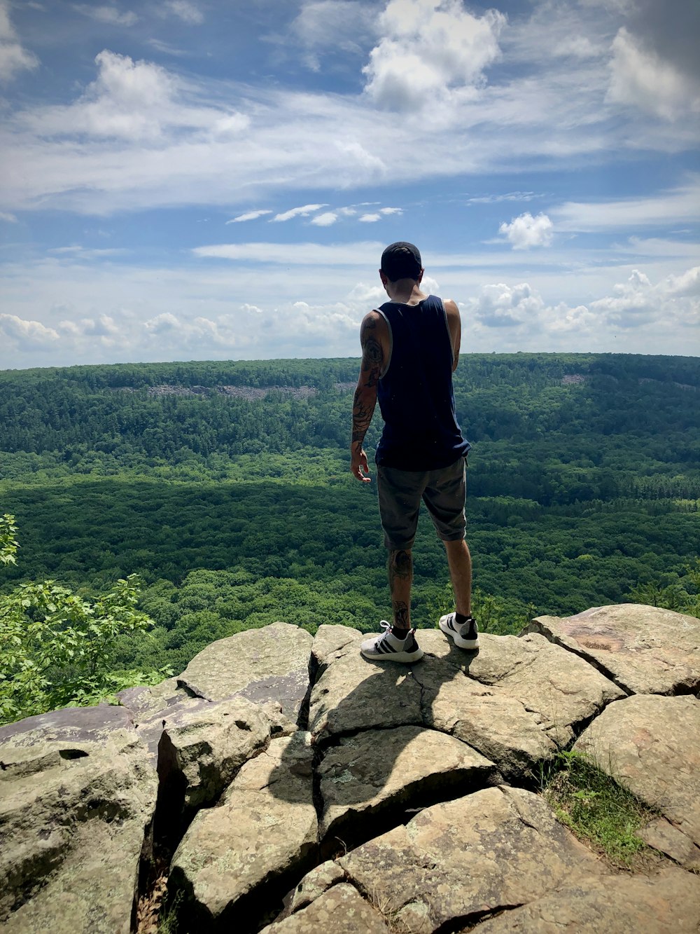 man in black t-shirt standing on rock during daytime