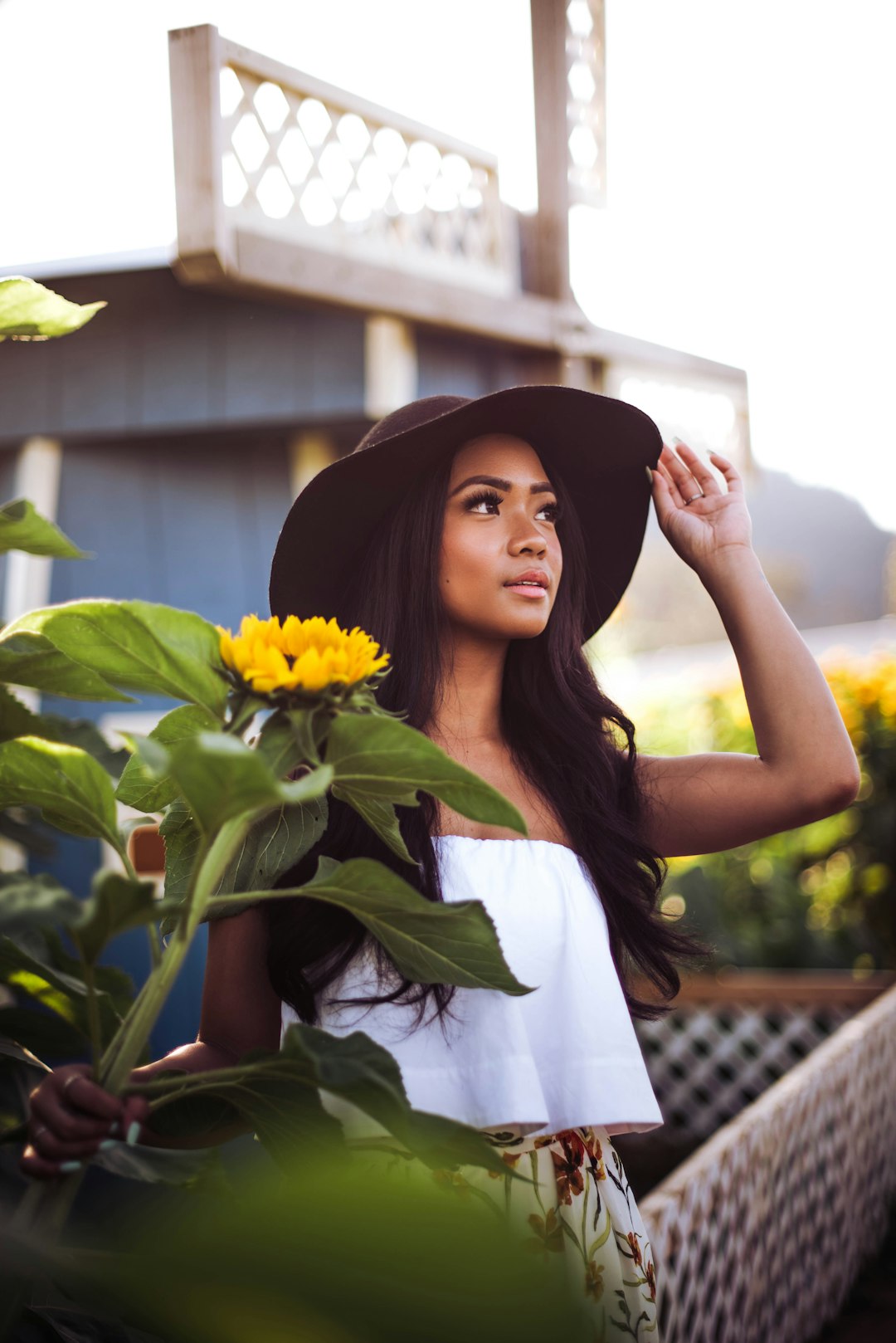 woman in white tank top holding yellow flower