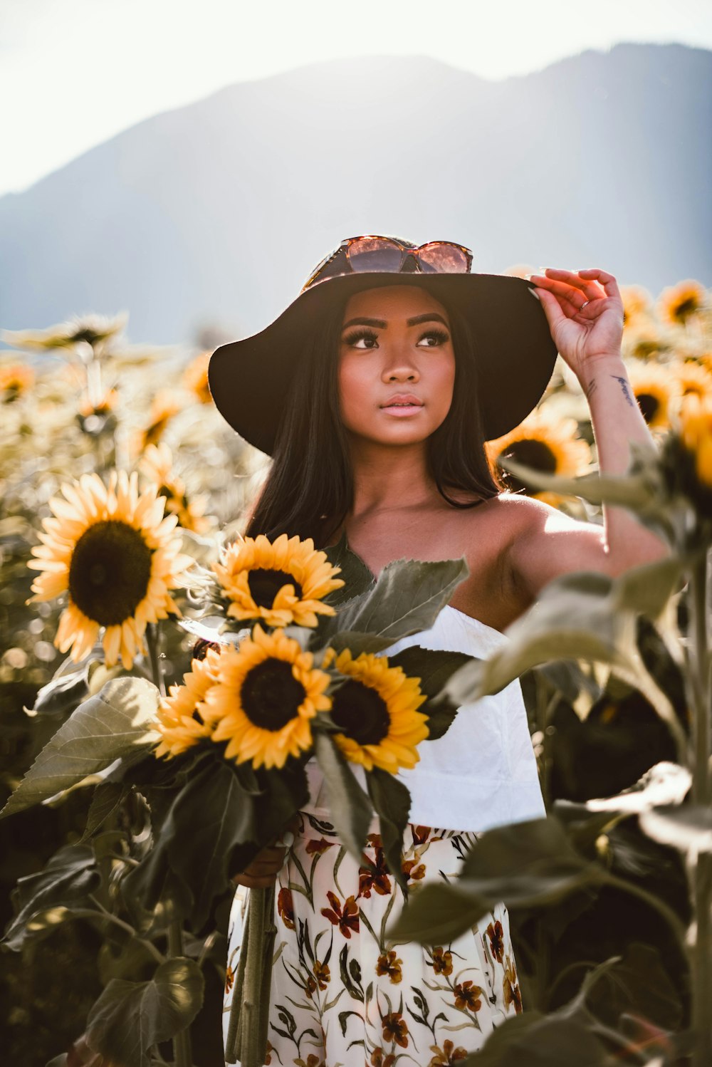 woman in black off shoulder dress standing on sunflower field during daytime