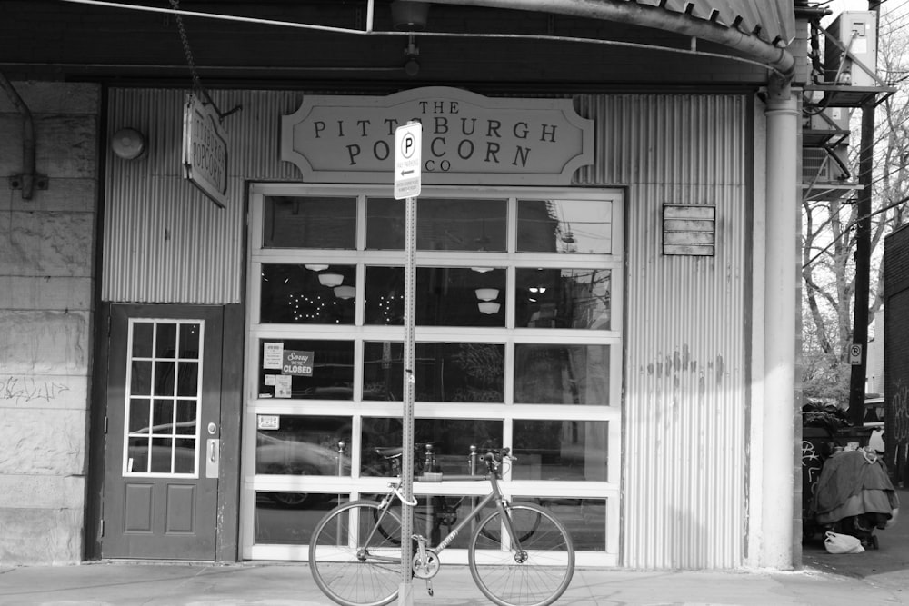 grayscale photo of bicycle parked in front of store